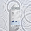 ROUND LAB 1025 Dokdo Cleansing Water bottle with blue cleansing water against a bubbly water background