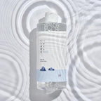 ROUND LAB 1025 Dokdo Cleansing Water bottle with blue cleansing water against a bubbly water background