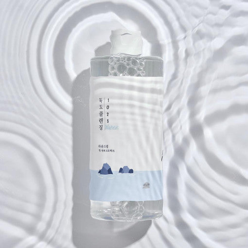 ROUND LAB 1025 Dokdo Cleansing Water bottle with blue cleansing water against a bubbly water background