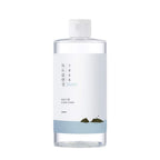 ROUND LAB 1025 Dokdo Cleansing Water bottle with blue cleansing water against a bubbly water background
